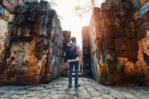 Prasat Muang Sing에서 내부를 걷는 남자 배낭은 역사 공원에 있는 크메르 사원의 고대 유적입니다