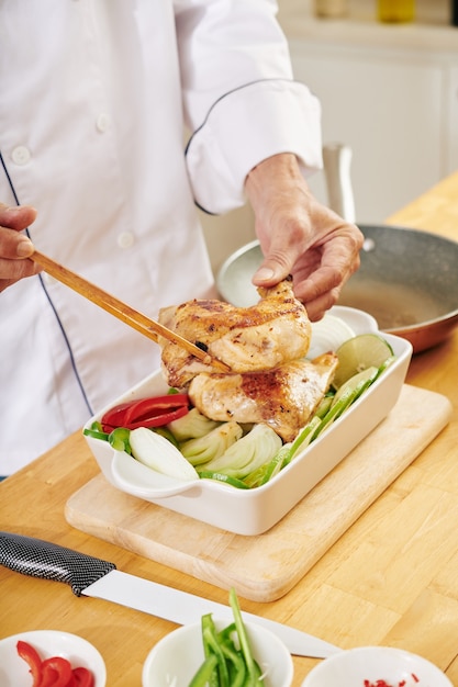 Man baking chicken with vegetables