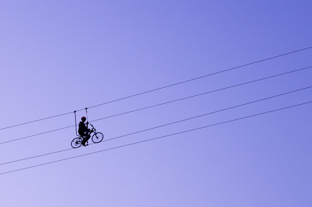 Man balanceren op een fiets aan een touw