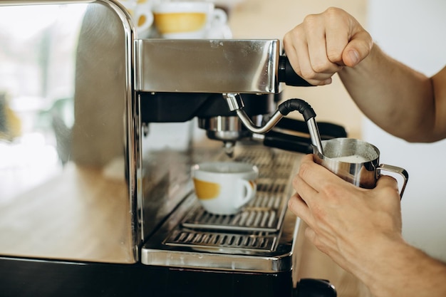 Man barista at coffe shop preparing coffee in a coffee machine