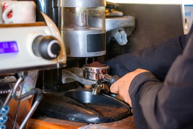 Man Barista maakt koffie maalpoeder op koffiezetapparaat