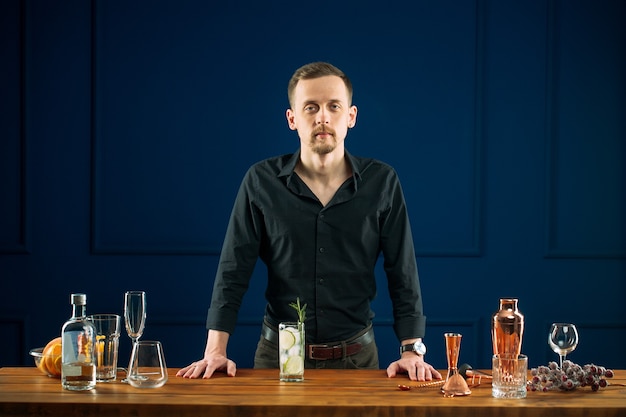 Man bartender standing behind desk with gin tonic