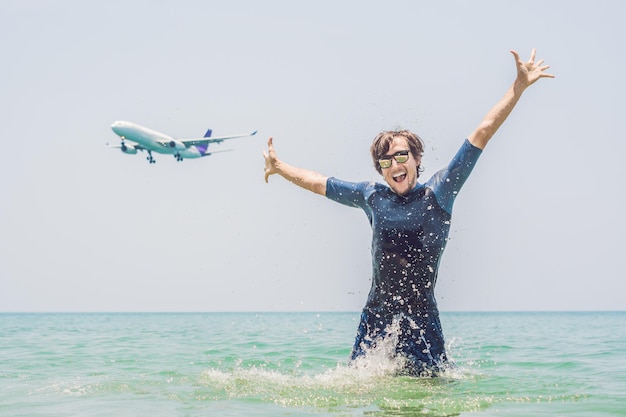 A man bathes in the sea, an airplane lands.