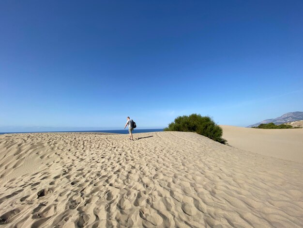 Man on beach against clear blue sky