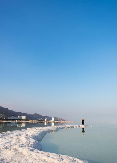 Man on beach against clear sky during winter