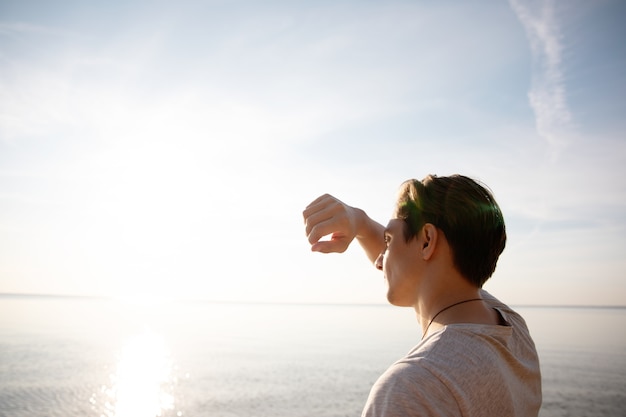 the man on the beach covers his face with his hands from the sun