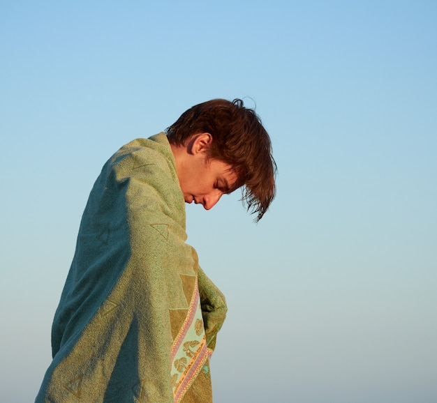 A man on the beach drying himself with a green towel