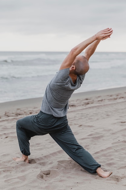 Foto uomo sulla spiaggia a praticare yoga meditazione