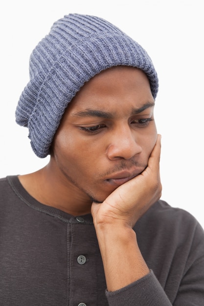 Man in beanie hat thinking with head on hand