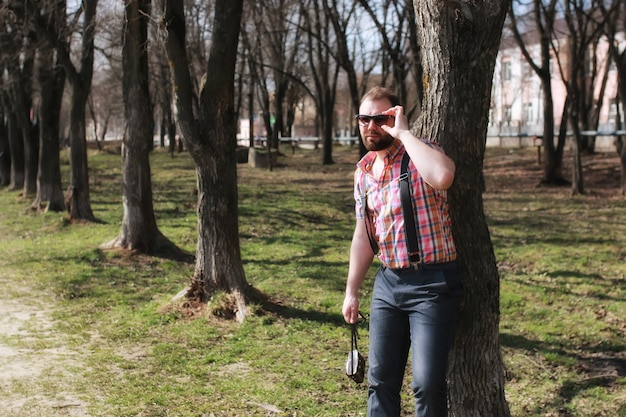 Man beard suspender tree park sunglasses
