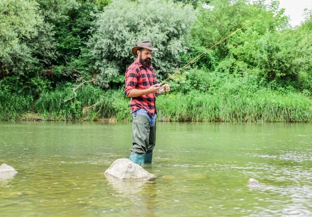 Man bearded fisherman Fish farming pisciculture raising fish commercially River lake lagoon pond Trout farm Fisherman alone stand in river water Fisherman fishing equipment Hobby sport activity