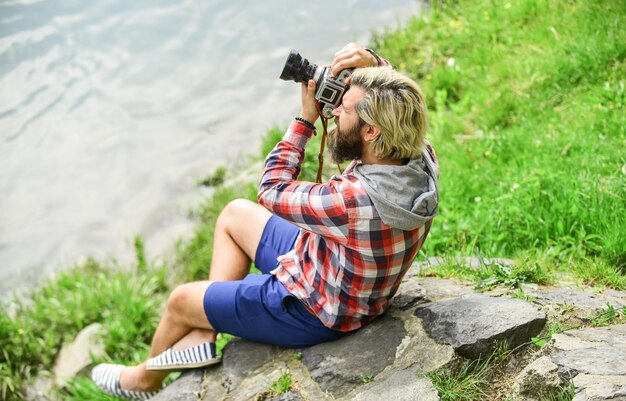 Man bearded hipster photographer hold vintage camera Photographer concept Photographer amateur photographer nature background Content creator Masterpiece shot Man with beard shooting photos
