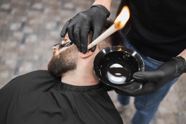 Man in a beauty salon is removing earwax using candles