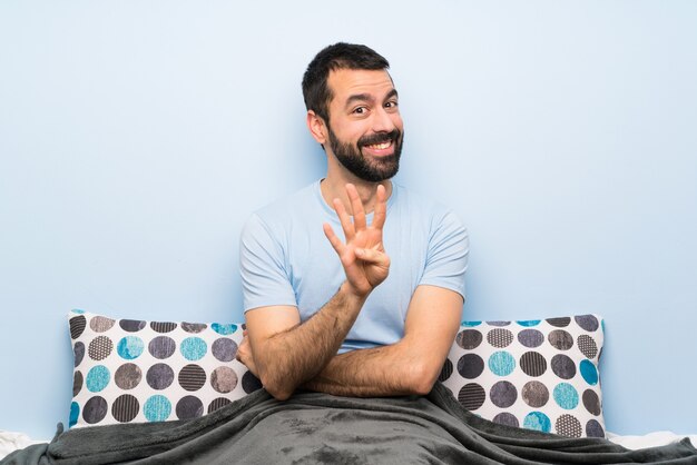 Man in bed happy and counting four with fingers