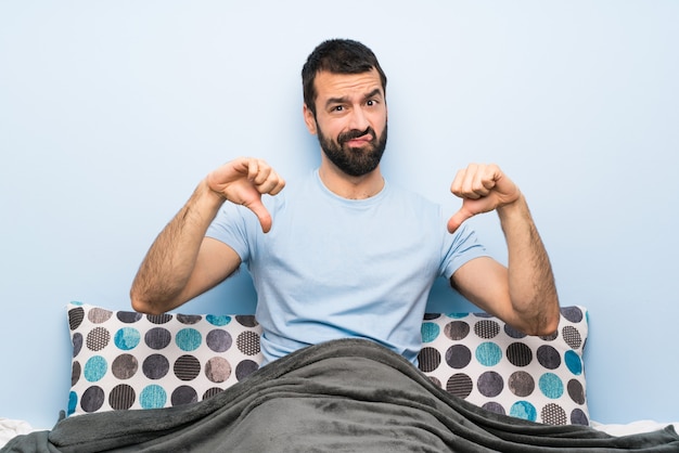 Man in bed showing thumb down