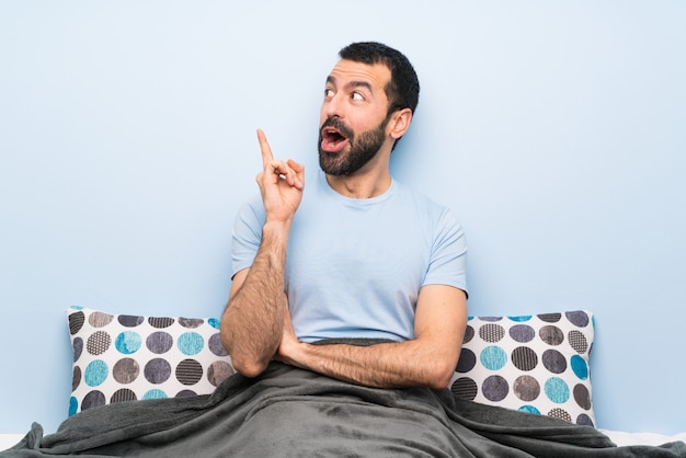 Man in bed thinking an idea pointing the finger up