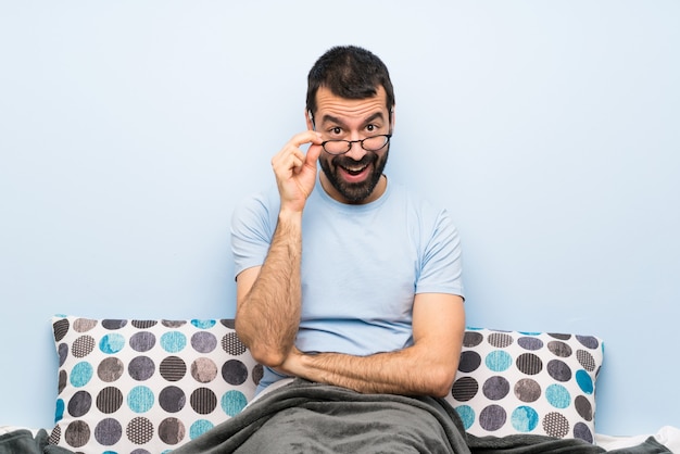 Man in bed with glasses and surprised