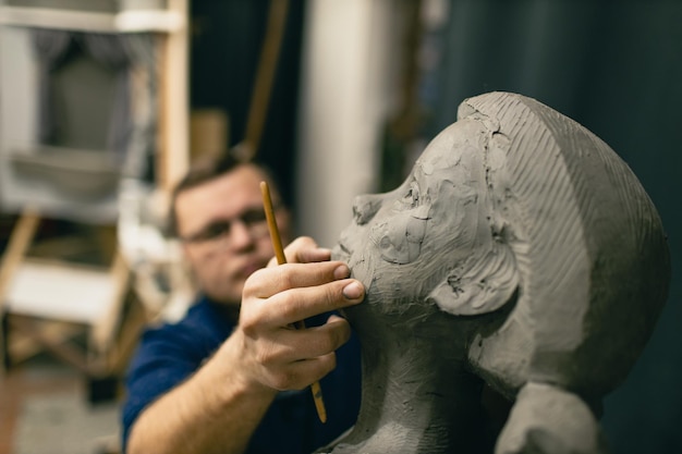 Man beeldhouwer maakt buste klei menselijke vrouw sculptuur Standbeeld ambachtelijke creatie workshop