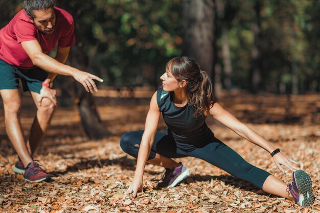 Man begeleidt vrouwelijke atleet die oefent op het veld in het bos