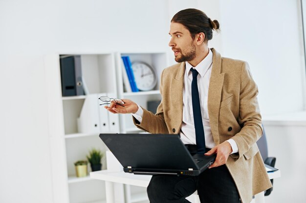 Man in beige jacket holding a phone laptop office technologies High quality photo