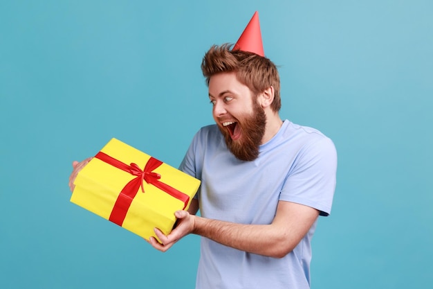 Man being very glad to get present from friend or girlfriend\
holding gift box expressing excitement