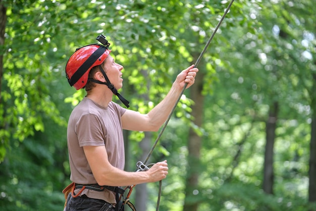 L'uomo assicura il suo compagno di cordata con dispositivo di assicurazione e corda. handman dello scalatore che tiene l'attrezzatura per la sicurezza dell'alpinismo su roccia.