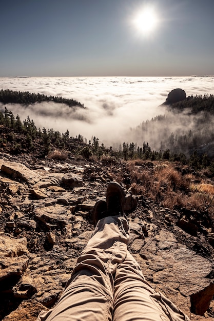 Man benen oogpunt met actieve trekking mensen rusten op de rotsen en genieten van het prachtige wilde panorama met bergen en bos op de wolken en de lucht in backgorund