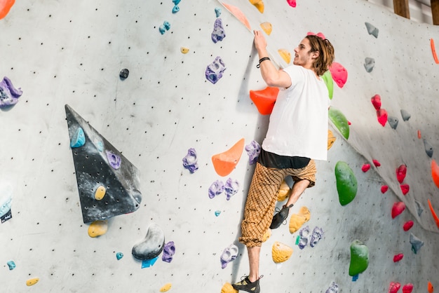 Man beoefenen bergbeklimmen op kunstmatige muur