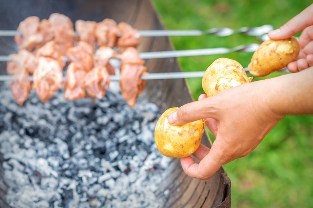 Man bereidt barbecuevlees met aardappelen