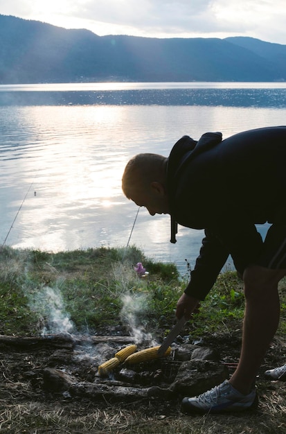 Man bereidt maïs voor bij het meer op barbecue