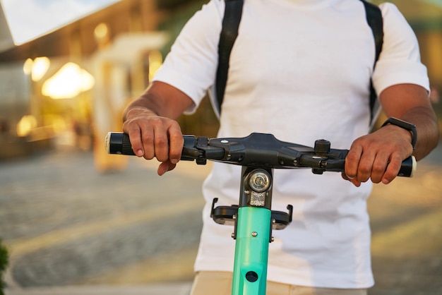 Man bereidt zich voor op het rijden op de elektrische eco-scooter op straat, selectieve focus. Vervoer