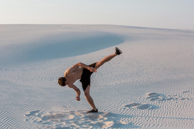 Man bestudeert parkour alleen. Acrobatiek in het zand