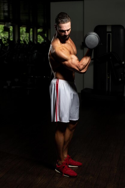 Man biceps trainen in een sportschool halter concentratie krullen