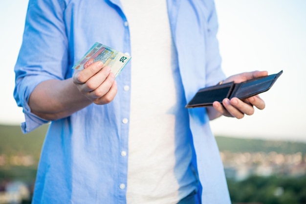 Man bijsnijden weergave met geld bankbiljetten en portemonnee in handen buitenshuis