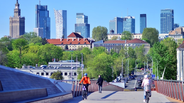 Photo a man on a bike is riding over a bridge with a city in the background