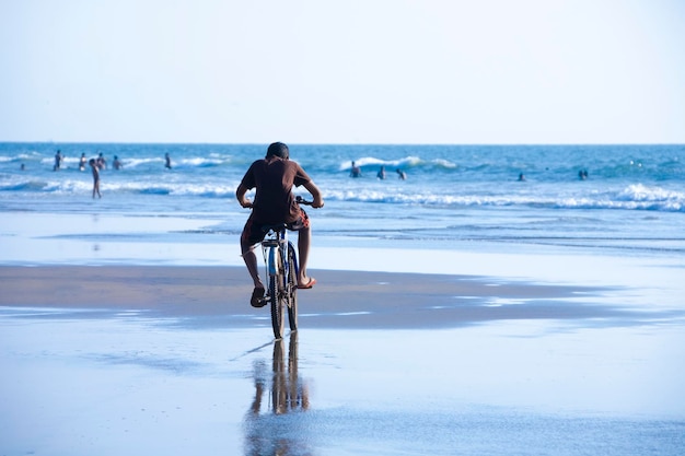 Man on bike riding along the beach