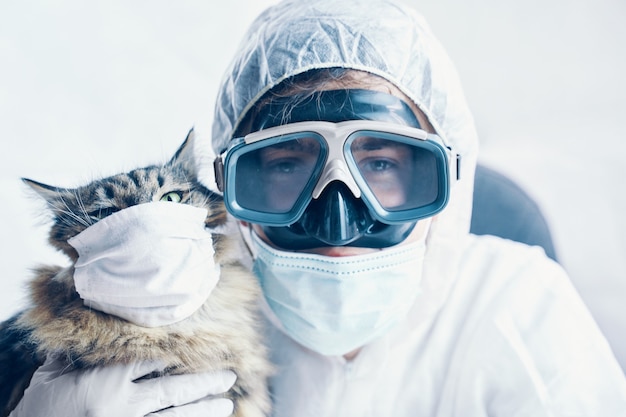 Uomo in tuta a rischio biologico e gattino con maschera di protezione