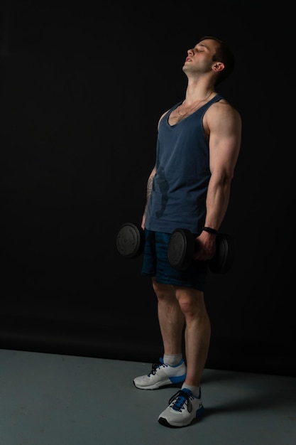 Man on black background keeps dumbbells pumped up in fitness\
active sexy black athlete training it