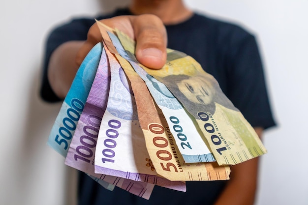 A man in black clothes holding the Indonesian money Indonesian rupiah banknotes