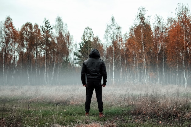 Uomo in un cappotto nero in tempo nebbioso