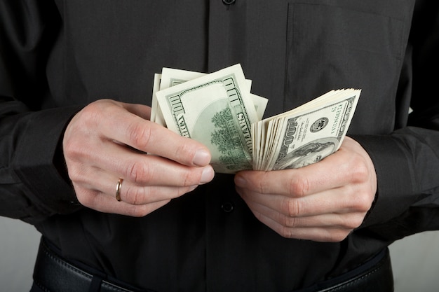 Man in black counts money dollars in hands