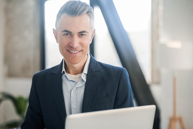 Photo man in a black elegant suit with a laptop