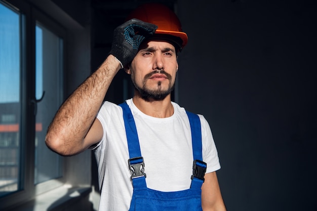 A man in black gloves and a blue overalls puts a helmet on his head
