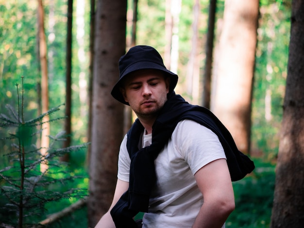 Ð man in a black hat sits in the woods