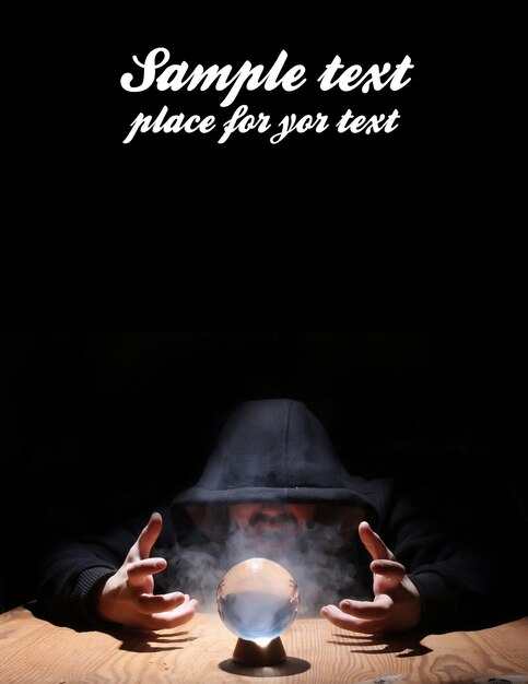 Photo man in a black hood with cristal ball summon evil and empty space for text