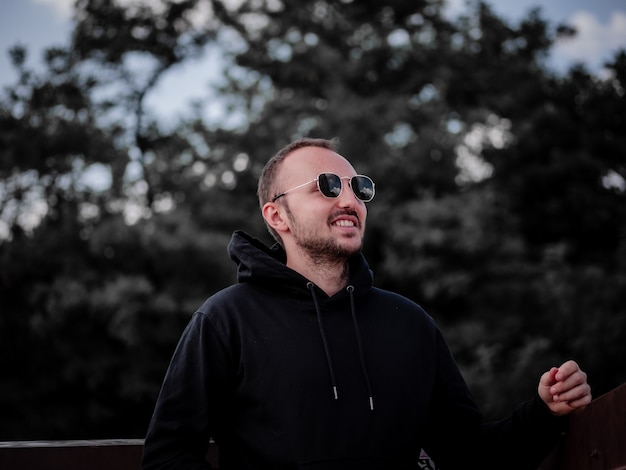 Man in black hoodie and sunglasses smiling