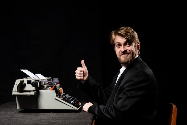 Man in a black jacket typing on a typewriter