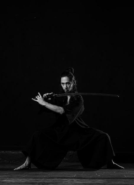 A man in a black kimono with a sword in his hand.