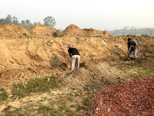 A man in a black shirt is digging in a pile of dirt