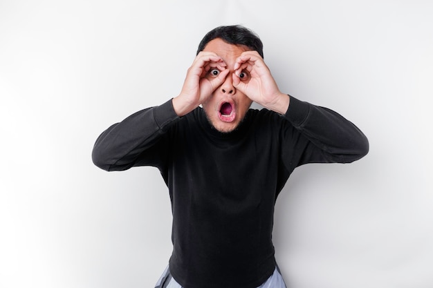 A man in a black shirt is looking through his fingers and is looking through his eyes.